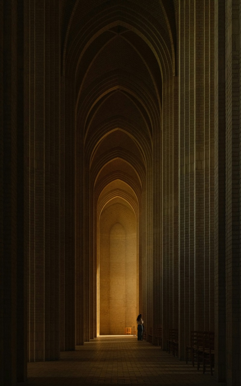 A person in a long vaulted brick corridor